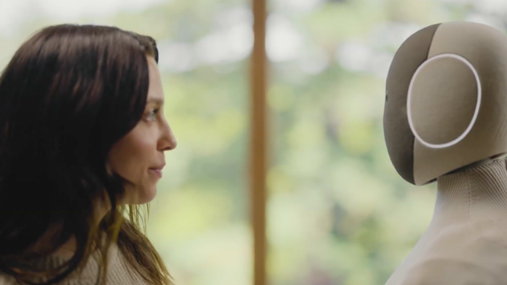 Woman greets 1X NEO humanoid robot in marketing video